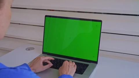 Person types on a laptop with a green screen in a modern workspace during d.. Stock Footage 340189428