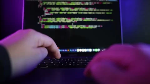 A person typing and scrolling on a laptop in a modern dark office. Stock Footage 336474148
