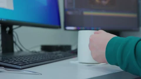A person is typing on a computer and taking a sip from a cup of coffee Stock Footage 277577118