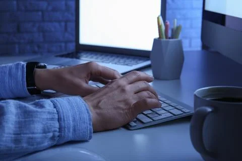 Person typing on computer keyboard at night, remote work and online communica Stock Photos