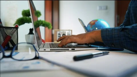 Person Typing at Desk with Globe and Calendar Stock Footage 317736628