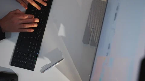 A person is typing on a keyboard in front of a computer monitor Stock Footage 302443272