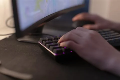 A person is typing on a keyboard in front of a computer Stock Photos
