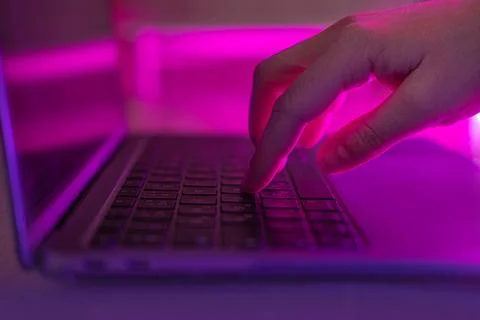 Person typing at laptop computer at night. Female uses keyboard, shakes but.. Stock Photos