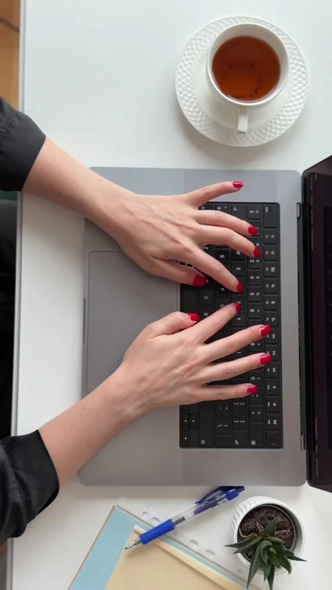 A person typing on a laptop with a cup of tea nearby. Video stock 340526551