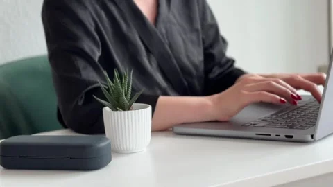 A person typing on a laptop at a modern workspace with plants. Vidéo 340526545