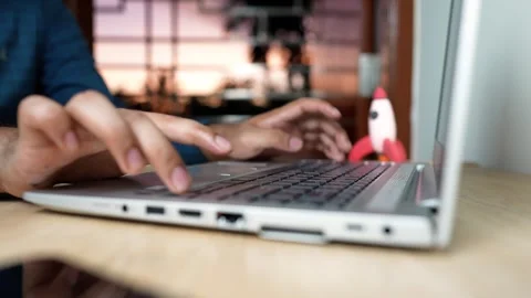 Person typing on a laptop with a small rocket model on the desk Stock Footage 320724317