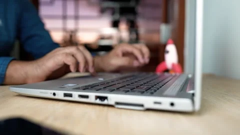 Person typing on a laptop with a small rocket model on the desk Stock Footage 320724360