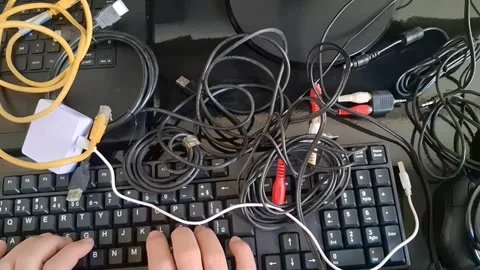 Person typing on a messy computer desk. Cluttered workspace with tangled cables Stock Footage 340241500