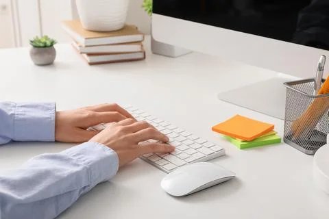 Person typing on a white computer keyboard with a mouse on a clean office des Stock Photos