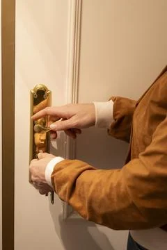 Person unlocking door using key and turning handle Stock Photos