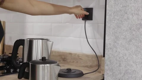 Person unplugging electric kettle from wall outlet in kitchen Stock Footage 344516672