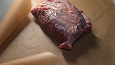A person unwraps a package containing a raw meat cut on a clean surface. Stock Footage 339097421