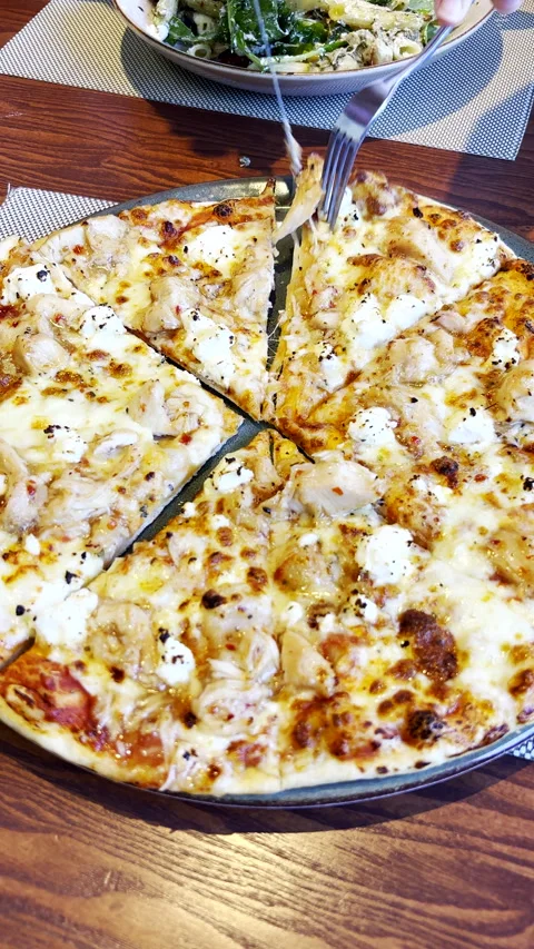 Person use knife and fork to take slice of creamy feta chicken pizza Stock Footage 329611630