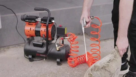 Person uses air compressor to clean dirty fabric material outdoors. Vídeo Stock 334916993