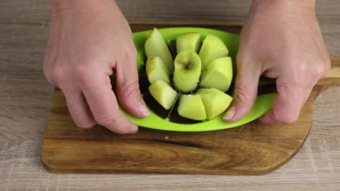 The person uses an apple slicer, pressing it through the apple. Stock Footage 345575053