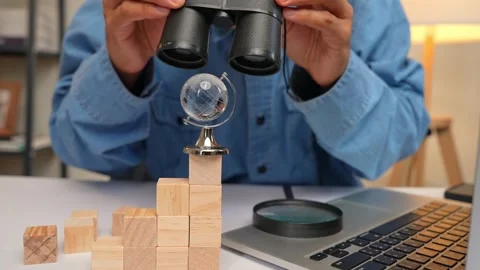 A person uses binoculars to observe a tiny globe. Stock Footage 316568153