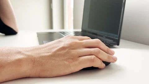 A person uses a black computer mouse while working on a laptop at a white office Stock Footage 315783183