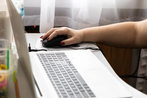 A person uses a black computer mouse on a desk with a white laptop to perfo.. 库存照片