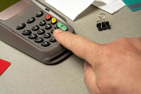 A person uses a card reader at a counter. The hand is pressing a button on .. Stock Photos