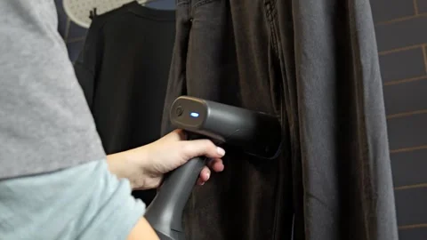 Person uses a garment steamer to remove wrinkles Vídeo Stock 333912330