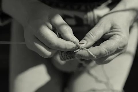 A person uses hands to guide a thread through a needle while sitting outside. Stock Footage 336464815