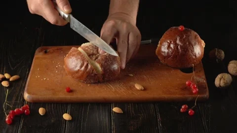 A person uses a knife to slice a loaf of fresh bread Stock Footage 321355071