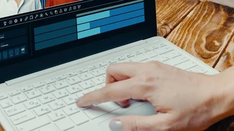Person uses laptop to create deep fake video in a bright room with wood table 写真素材