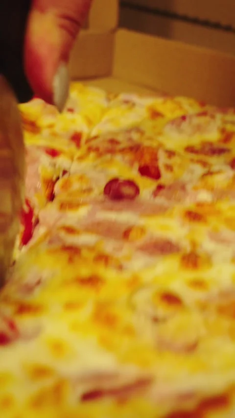 A person uses a pizza cutter to slice a fresh pizza in a kitchen Stock Footage 345203418
