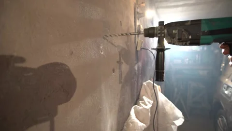 A person uses a power drill to make holes in a wall for installation or repair, Stock Footage 332227343