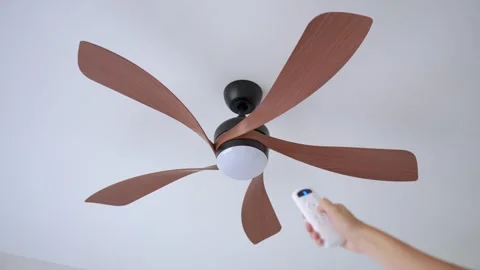 Person uses remote control to operate ceiling fan mounted on ceiling Stock Footage 340151192