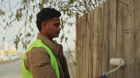 Person uses roller to renew worn planks along roadside. Professionally painting Stock Footage 345154966