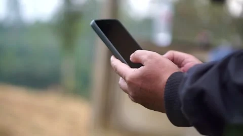A person uses a smartphone with both hands outdoors. Stock-Footage 336501082