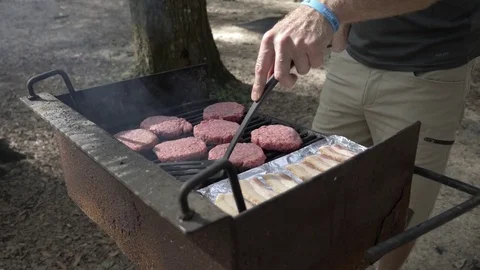 Person Uses Spachula to Press down on Burgers Cooking Stock Footage