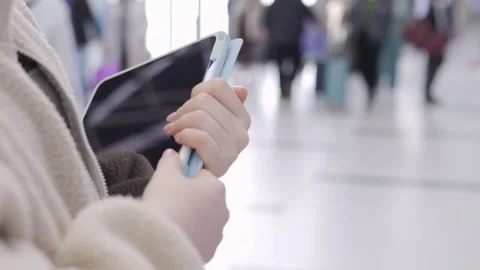 Person uses tablet and stylus while walking through busy airport terminal Stock Footage 343595279