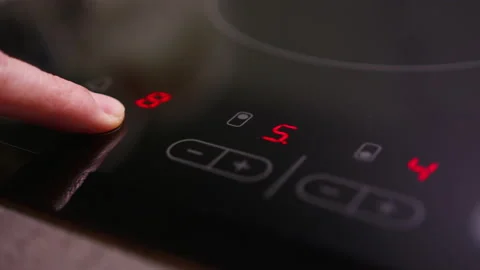 Person uses the time settings of an induction cooktop, cycles through Stock-Footage 166601693