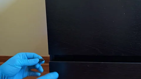 Person uses a tool to fix a drawer with blue gloves in a home setting during Stock Footage 331305308