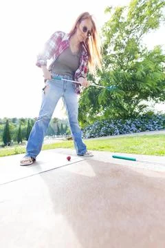 Person uses a tool to work on a surface in a green outdoor area on a sunny day Stock Photos