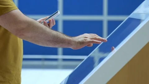 Person uses touch screen kiosk while holding mobile device Stock Footage 345710816