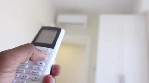 Person using air conditioner remote control to adjust home temperature and .. Stock Footage 332786443