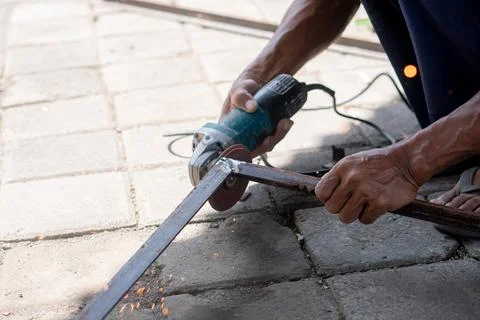 Person using angle grinder to cut metal outdoors Stock Photos