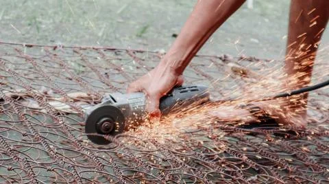 A person is using an angle grinder to cut through a metal spring mattress, .. Foto stock