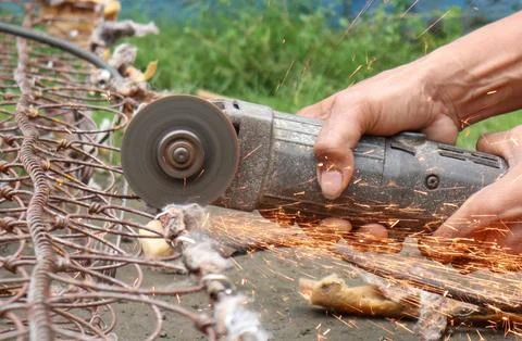 A person is using an angle grinder to cut through a metal spring mattress, .. Stock Photos