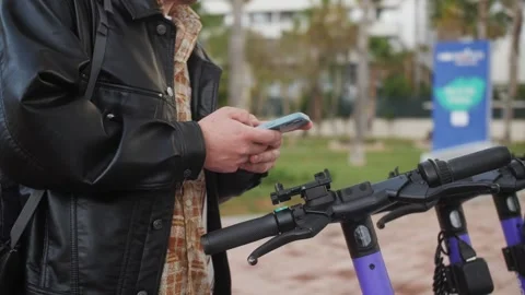 Person using app on phone to unlock electric scooter on the street. Stock Footage 241139441