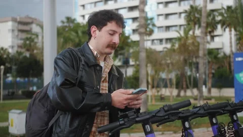 Person using app on phone to unlock electric scooter on the street. Stock Footage 257681267
