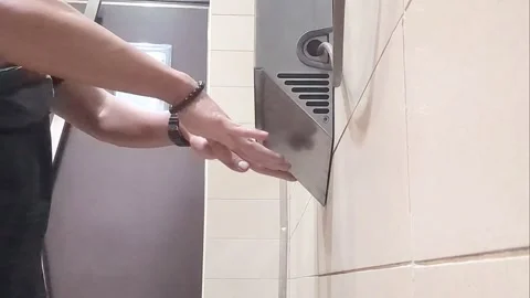 Person Using Automatic Electric Hand Dryer in Public Restroom Stock Footage 328714102
