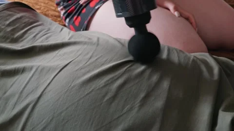 Person Using Black Percussion Massage Gun on Partners Back at Home Stock Footage 335230097
