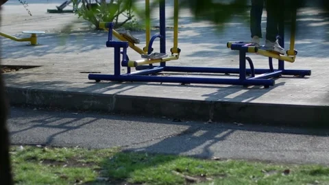 Person using blue and yellow outdoor elliptical exercise machine Stock Footage 332293280