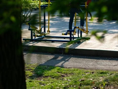 Person using blue and yellow outdoor elliptical exercise machine in a publi.. Stock Photos
