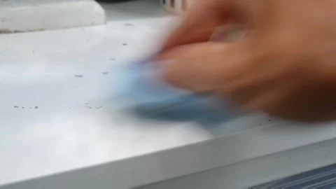 Person using blue microfiber cloth to wipe dirt from white outdoor countertop Stockbeeldmateriaal 333443269